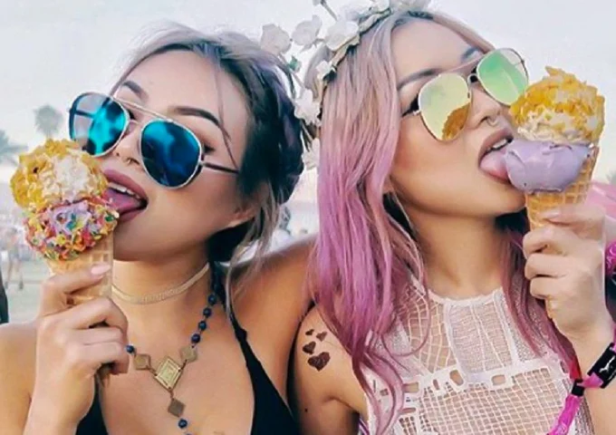 Two women in stylish Ray-Ban BLAZE AVIATOR RB3584N Sunglasses enjoying ice cream cones topped with colorful toppings, decorated with accessories.